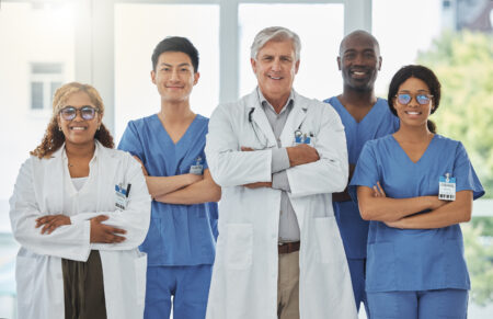 Happy portrait, arms crossed and group of doctors standing together in hospital. Face, teamwork and confident medical professionals, nurses and surgeons with collaboration, healthcare and support